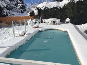 圣卡洛斯-德巴里洛切HOTEL LE CHARME con parking的一座游泳池,里面被雪覆盖着,配有桌椅