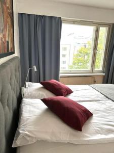 赫尔辛基Spacious 2 rooms apartment in Helsinki Design District, own balcony的床上的2个红色枕头,窗户