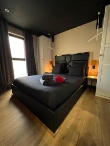 南希Les suites de Stanislas jacuzzi & spa的一间卧室配有一张带鲜花的大型黑色床。