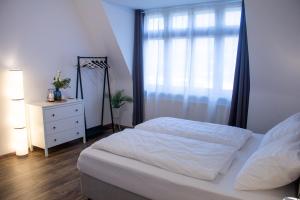威斯巴登BeMyGuest - 3 Zimmer Maisonette - Zentral - Klimaanlage - Aufzug的一间卧室配有一张床、一个梳妆台和一扇窗户。