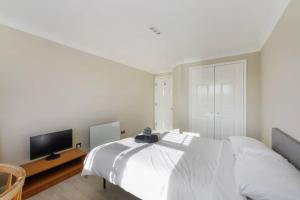 泰晤士河畔金斯顿Luxury Apartment in Kingston的一间白色卧室,配有床和电视