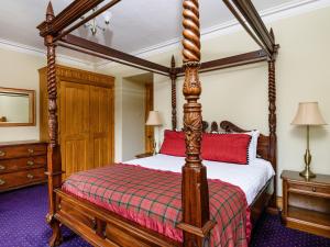 MoulinGatehouse Lodge的一间卧室配有一张带红色枕头的四柱床