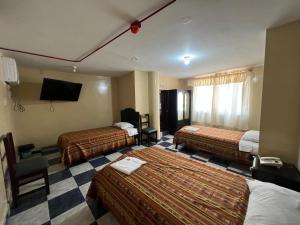 HuaquillasHotel RODEY的一间酒店客房,设有两张床和电视