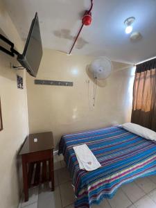 HuaquillasHotel RODEY的一间卧室配有一张带书桌的床和一台电视。