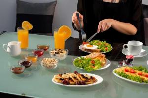 伊奥斯乔拉Ambiente Luxury Suites的女人在餐桌上吃着食物,盘子里放着食物