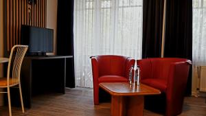 林根Appart-Haus Business Apartments的一间带电视的客房内的两张红色椅子和一张桌子