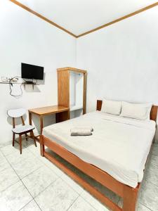巴东Wisma Mutiara的一间卧室配有一张床、一张书桌和一台电视