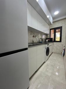 SuramiSurami的厨房配有白色橱柜和洗衣机。