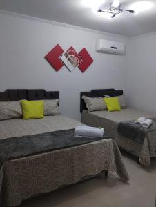 伊塔蒂亚亚Hospedagem Encantos da Serra的一间卧室配有两张带黄色和红色枕头的床
