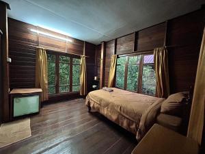 达叻府苏察纳里兰戈普度假村的卧室设有木墙、床和窗户。