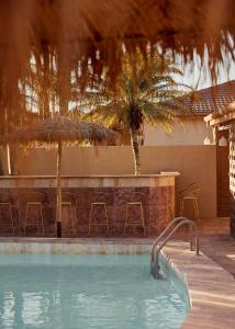 拜伦湾Swell Hotel Byron Bay - Adults Only的游泳池,设有配备椅子和棕榈树的酒吧