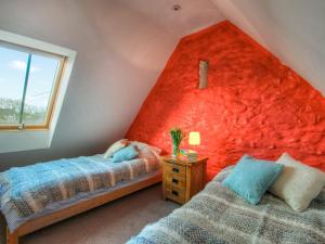 圣大卫Rhosson Chapel Cottage的红色墙壁的客房内的两张床