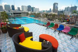 曼谷维初安公寓式酒店的阳台配有五颜六色的椅子,大楼内设有一个游泳池