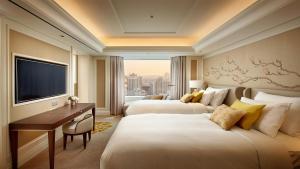 首尔首尔乐天酒店的配有书桌和电视的酒店客房内的两张床