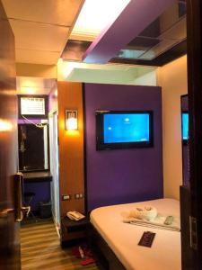 杜马格特Harimariz Dormitory Official的卧室设有紫色墙壁,墙上配有电视