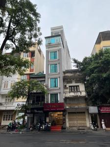 河内A25 Hotel - 88 Nguyễn Khuyến的一条高大的白色建筑,街上有蓝色的窗户