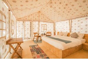 斋沙默尔Lakhina Heritage desert camp的卧室配有一张床和一张桌子