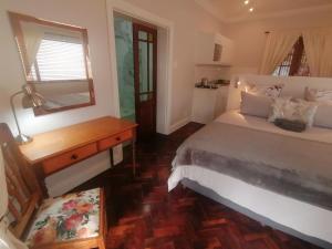 开普敦Beulah Lodge的一间卧室配有一张床、一张书桌和一面镜子