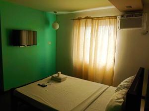 那牙Villa Rosita Hotel的一间卧室设有一张带绿色墙壁和窗户的床。