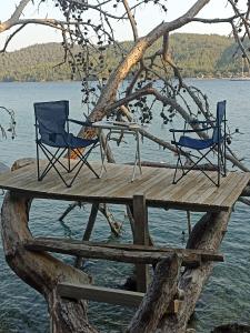 DağpınarSu camping的水面上木甲板上的两把椅子和一张桌子