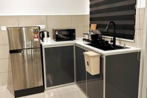 马六甲Biubiu Home的厨房配有不锈钢冰箱和微波炉。