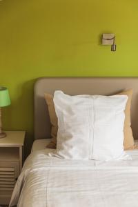 波佩林赫安菲拉宾馆的一张带白色枕头和绿色墙壁的床
