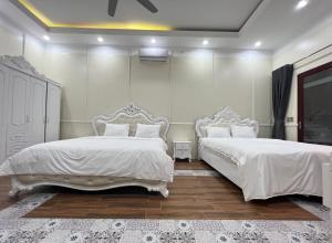 河江Golden Jungle House的卧室设有两张床,拥有白色的墙壁和木地板