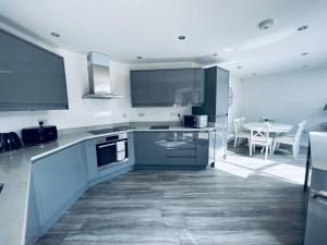 盖茨黑德Stunning 3-Bed Cottage in Gateshead的厨房配有蓝色橱柜和桌椅