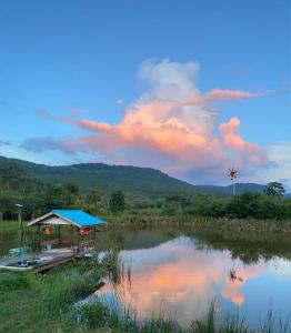 北冲Homtel Farmstay Campgrounds的一座蓝色屋顶的建筑,毗邻湖泊