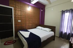 卡尔佩特塔Wayanad regal residency的紫色墙壁客房里一间卧室,配有一张床