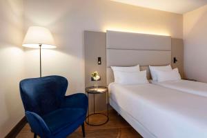 日内瓦NH日内瓦机场酒店的酒店客房,配有一张床和一张蓝色椅子