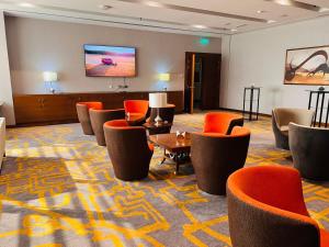 迪拜Lavender Hotel Al Nahda Dubai的酒店大堂设有橙色椅子和平面电视。