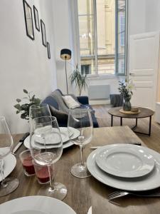 尼斯Sublime Appartement 2 pièces au cœur de la Vieille Ville的一张木桌,上面放有盘子和酒杯
