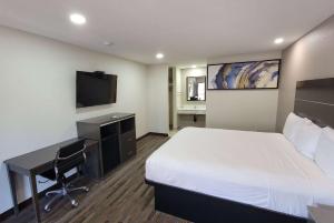 博伟公园普安那公园温德姆旅程住宿汽车旅馆的酒店客房配有一张床、一张书桌和一台电视。