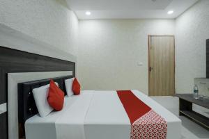 KurukshetraHotel Prime Rose的一间卧室配有一张带红色枕头的大床