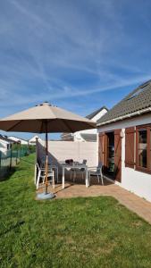 文代讷Vissershuisje 89 te Wenduine的一个带桌子和遮阳伞的庭院
