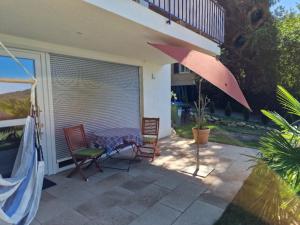 巴登韦勒Bellavista的庭院配有两把椅子、一张桌子和一把遮阳伞