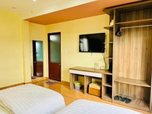 大叻Ngoc Tran Hotel的卧室配有一张床,墙上配有电视。