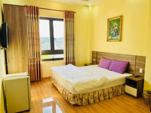 大叻Ngoc Tran Hotel的一间卧室配有一张带紫色枕头的床和窗户。