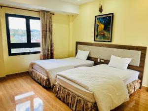 大叻Ngoc Tran Hotel的酒店客房设有两张床和窗户。