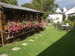BalveFerienwohnung Triska的花园内种有粉红色的鲜花,配有桌椅