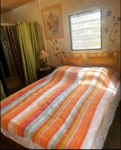 库鲁Maison de campagne的卧室内一张带五颜六色棉被的床