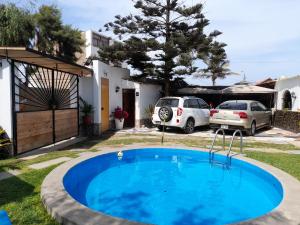 万查科Montemar Apart Hotel - Playa Huanchaco的一座房子的院子内的游泳池,有两辆车停放