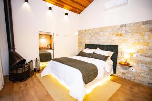 圣本图-杜萨普卡伊Chalés Quinta da Boa Vista的一间卧室设有一张大床和砖墙