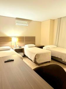 阿雷格里港Umbu Hotel Porto Alegre - Centro Histórico - Prox Aeroporto 15min的酒店客房设有两张床和一张桌子。