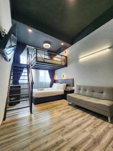 乔治市Georgetown Inn by Sky Hive的一间卧室配有高架床、一张床和一张沙发