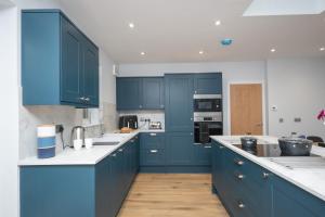 邓布兰Historical Holmehill Lodge的厨房配有蓝色橱柜和白色台面