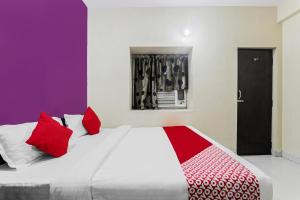 贾姆谢德布尔OYO Flagship Hotel Jagbamda的一间卧室配有一张带红色和白色枕头的大床