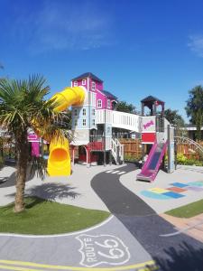 滨海布朗海洋露营地的粉红色建筑前的游乐场,带滑梯