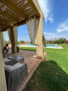 马拉喀什Dar Amali, villa spacieuse 9ch avec piscine en exclusivité的一个带桌子和游泳池的有盖庭院